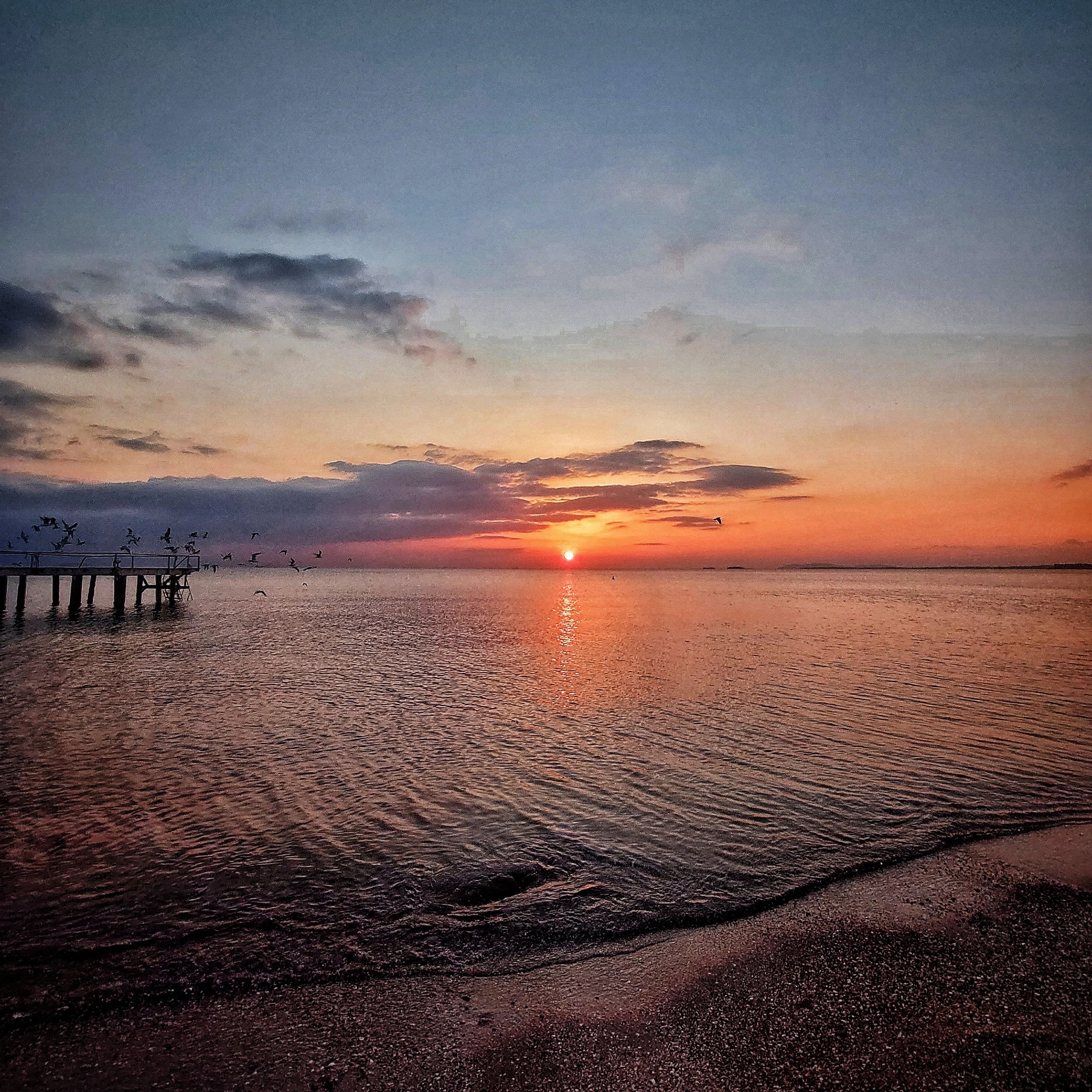 Calm ocean sunrise with soft clouds and warm light
